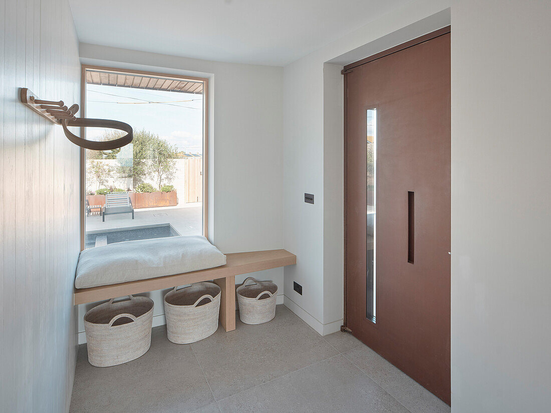 Modern entrance area with bench by the window and storage baskets