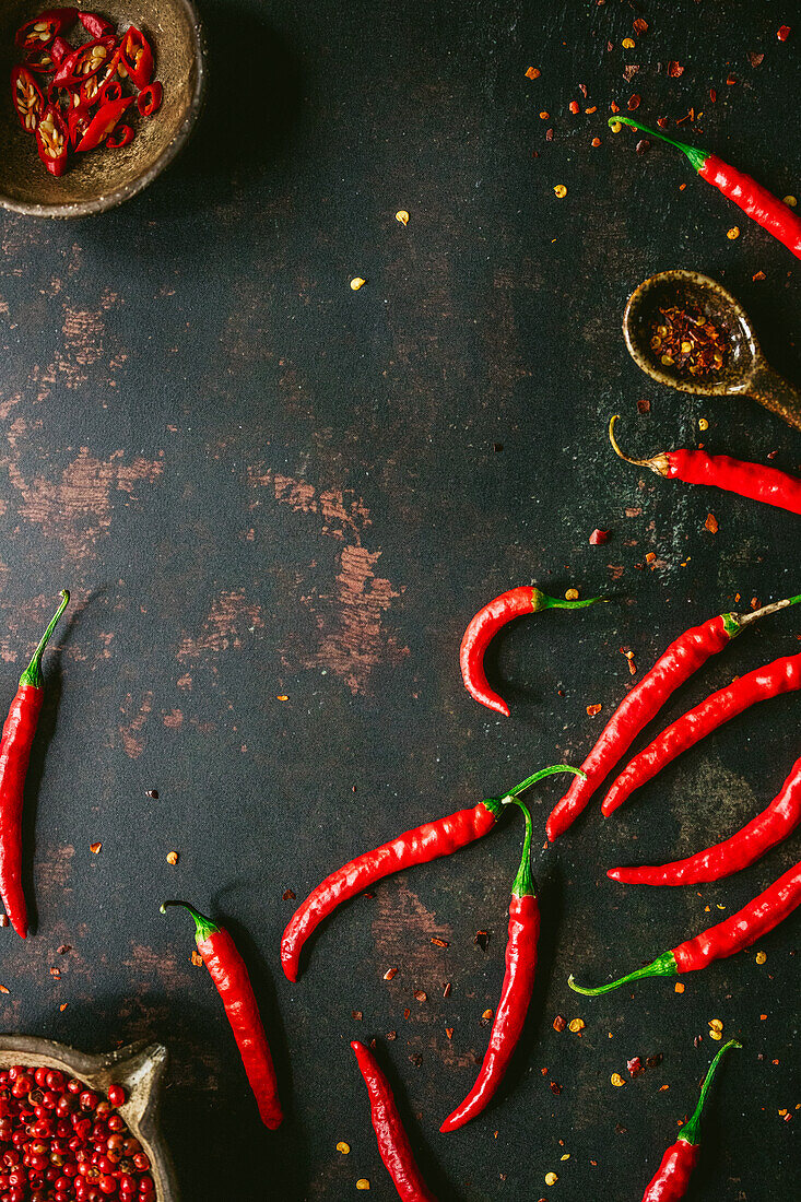 Rote Chilischoten und Chiliflocken auf schwarzem Hintergrund