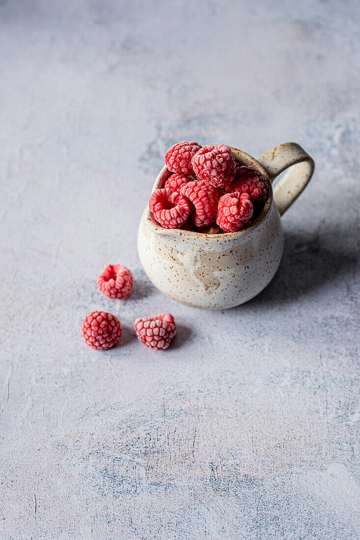 Gefrorene Himbeeren in einer Keramiktasse