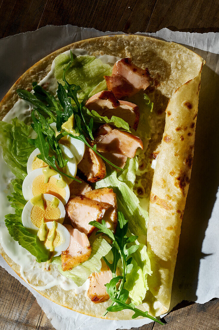 Tortilla wrap with salmon, egg, rocket and mustard-dill sauce