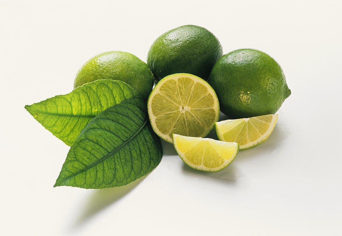 Three limes with leaves, lime half and slice