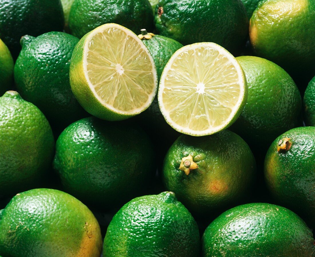 Many limes, one halved on top (close-up)