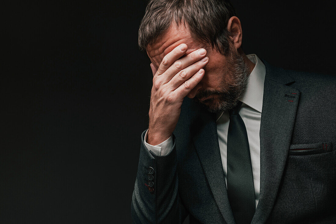 Disappointed businessman covering face