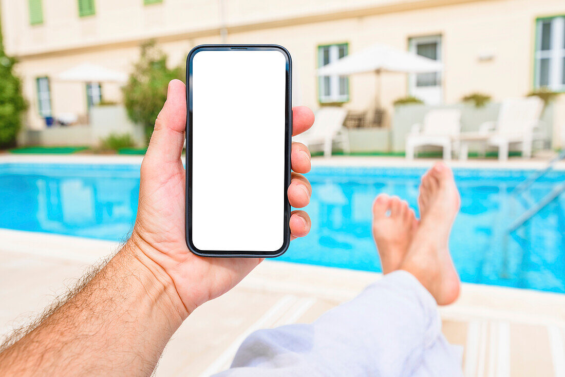 Man holding smartphone with blank screen by the pool