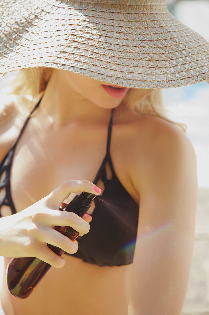 Young Woman Applying Suntan Lotion on her Arm