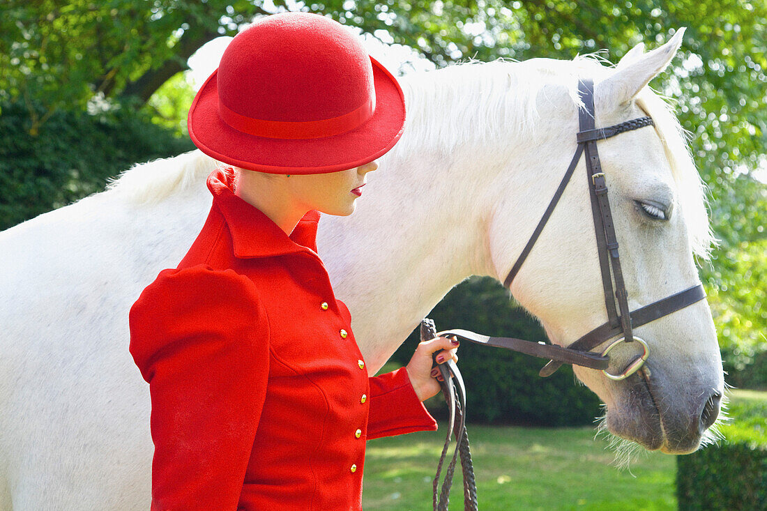 Frau in roter Reiterkleidung mit Pferd