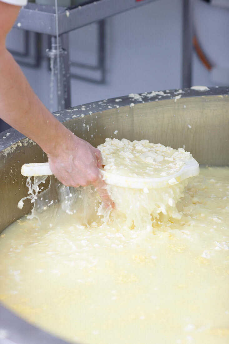 Nahaufnahme einer Männerhand beim Sieben von Käse