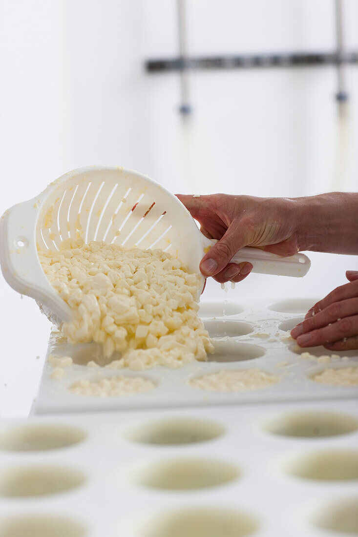 Nahaufnahme eines Mannes, der Käse in Formen glättet