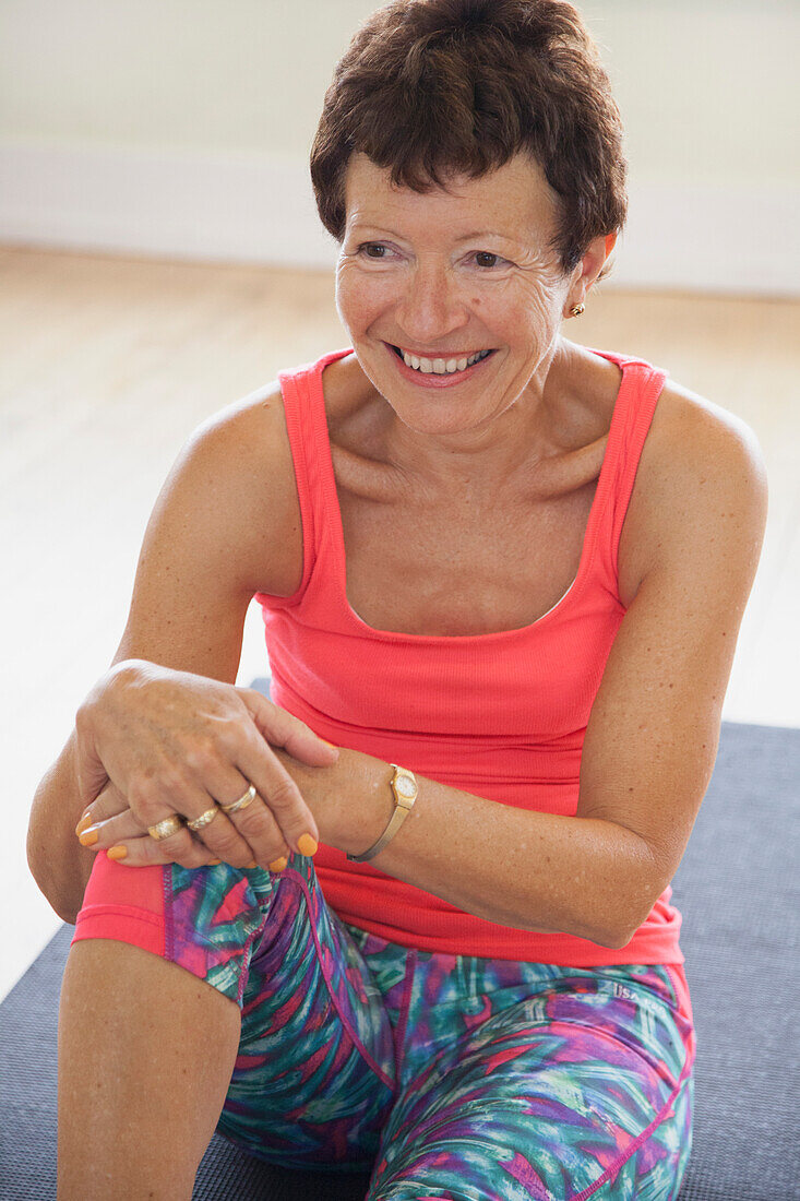 Smiling Woman Sitting on Exercise Mat