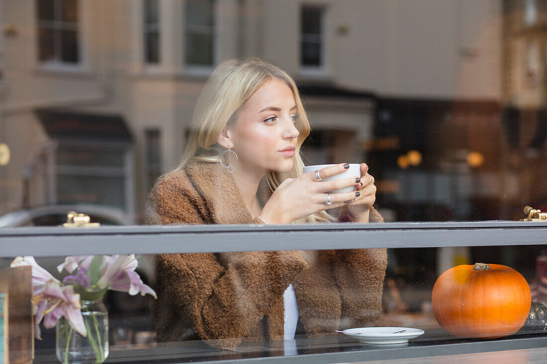 Junge Frau sitzt im Café und trinkt Kaffee