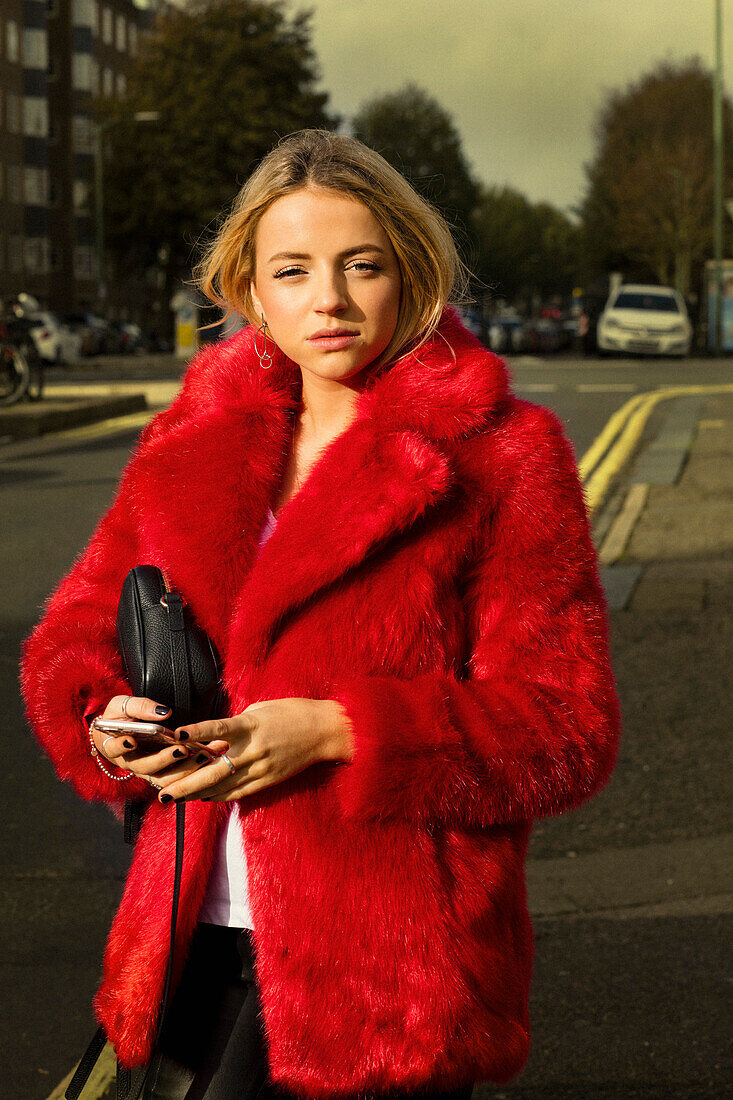 Woman Wearing Red Fake Fur Coat in City Street