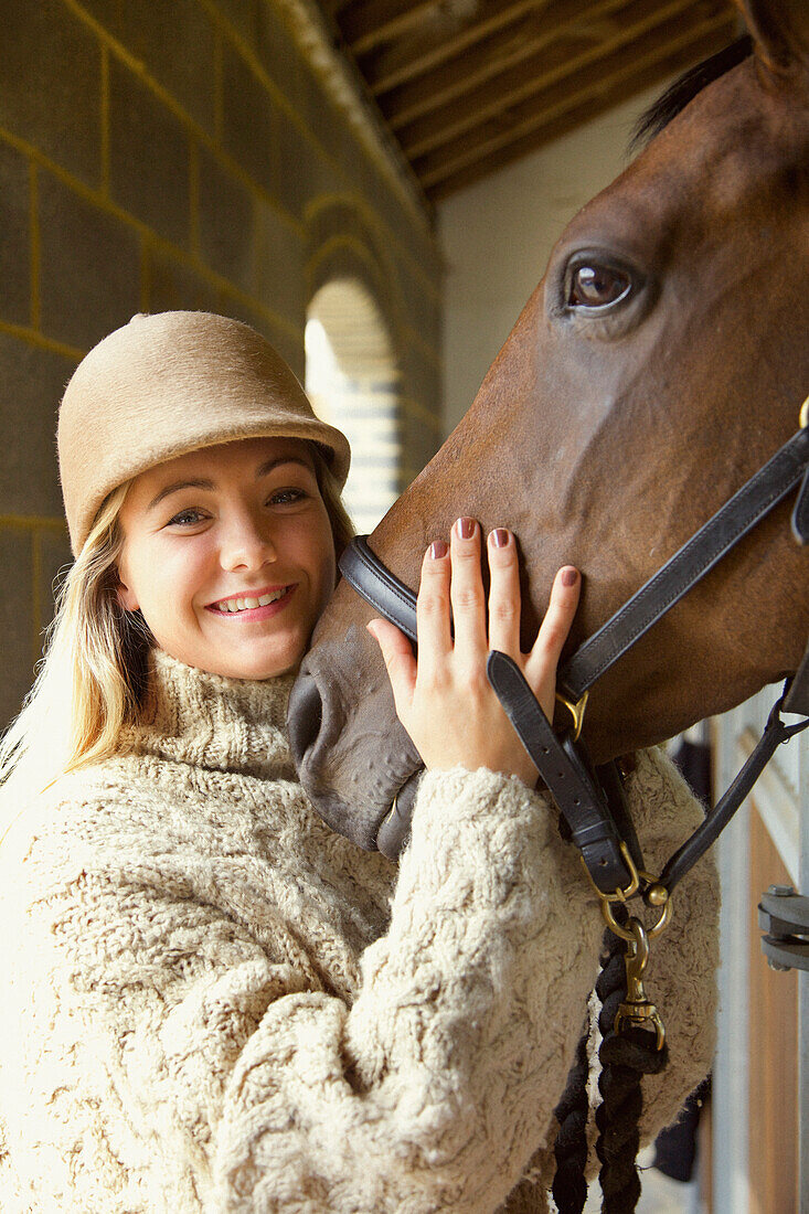 Smiling Young Woman Stroking Horse Head