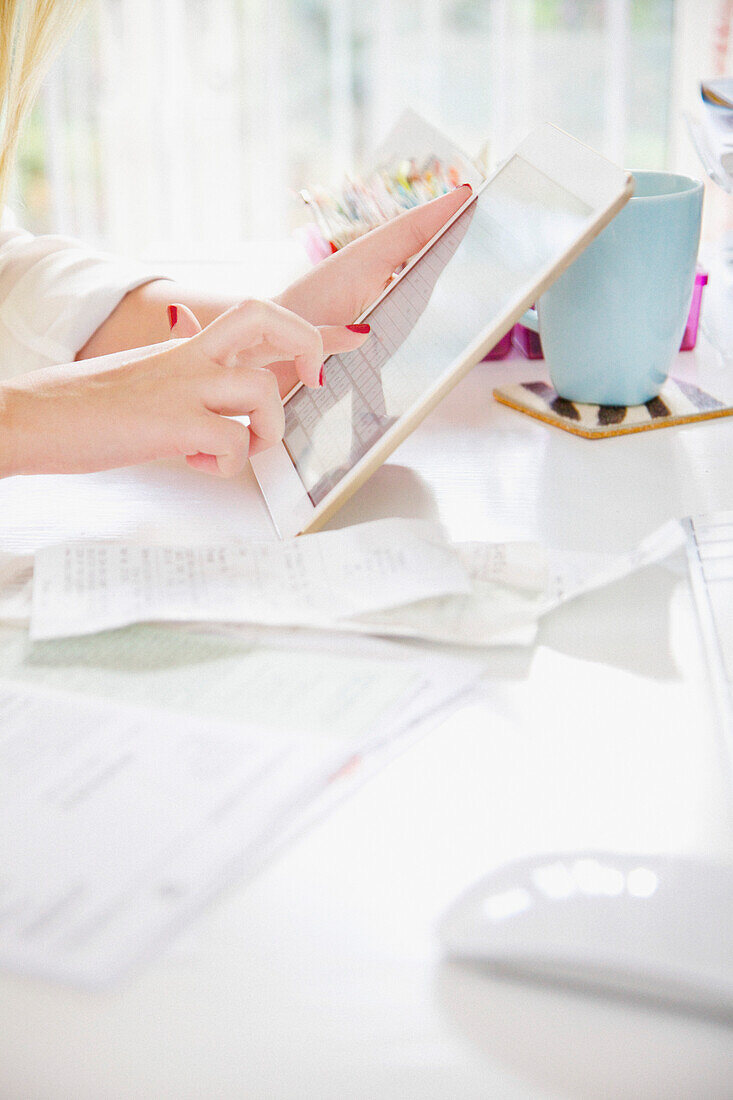 Woman Using Tablet Computer whilst Sorting Out Bills, Close-up View