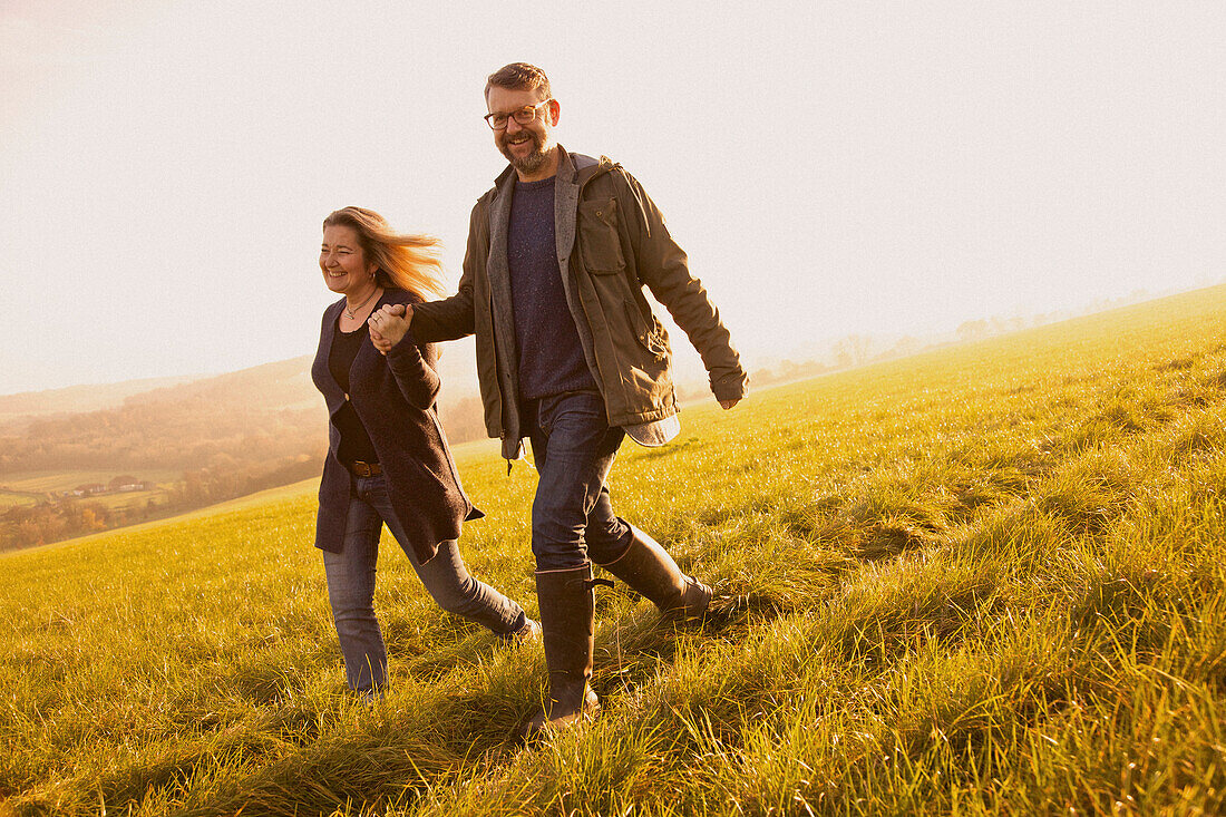 Smiling Couple Walking in a Field Holding Hands