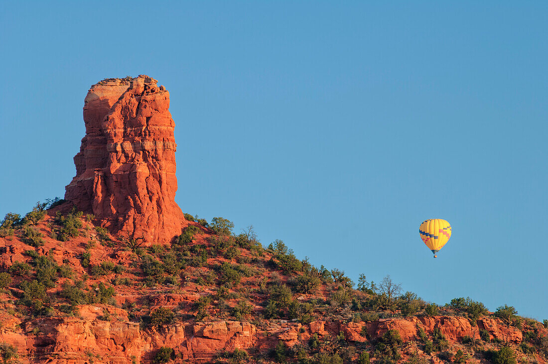 Chimney Rock and hot air balloon at sunrise, Sedona, Arizona.