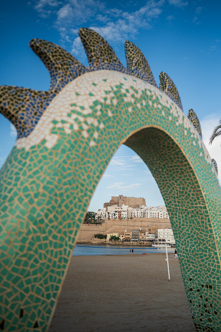 Blick auf die Burg Papa Luna durch die Drachenskulptur an der Strandpromenade in Peñiscola, Castellon, Valencianische Gemeinschaft, Spanien