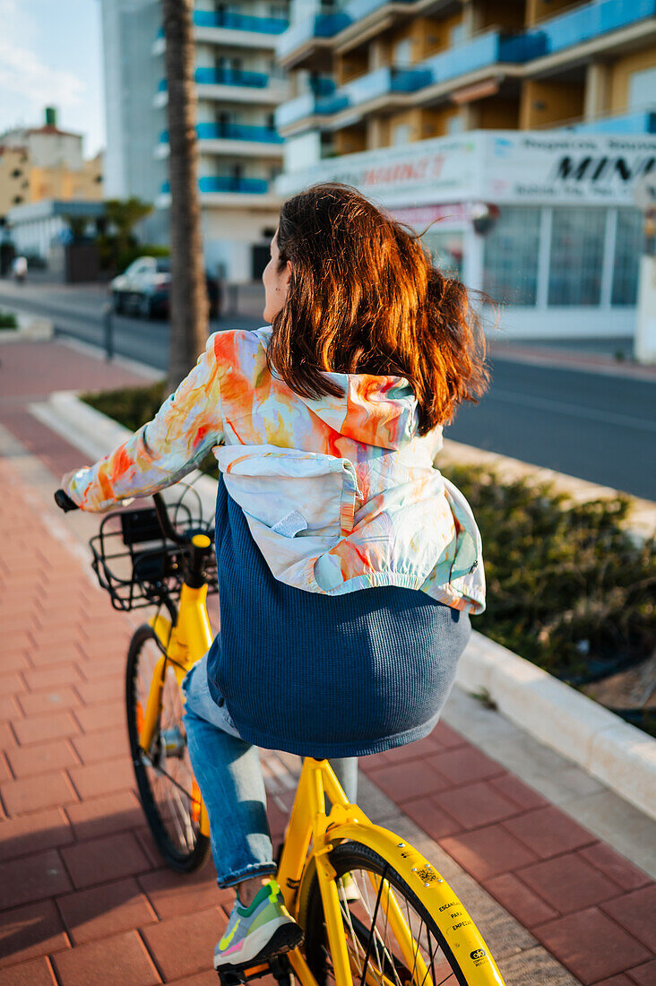 Woman rides a bicycle along the promenade, Peñiscola, Spain