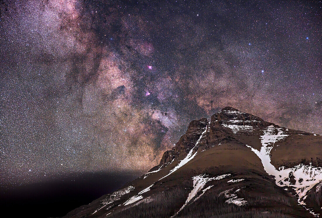 Die Milchstraße über dem Gipfel des Mt. Blakiston, im Waterton Lakes National Park, Alberta, Kanada. Dies war am 10. und 11. Juni 2024, so dass in großen Höhen noch etwas Schnee liegt. Dies ist ein Beispiel für ein Deepscape" - ein Nachtbild, das mit einem Objektiv mit längerer Brennweite als für Nachtbilder üblich aufgenommen wurde, um ein Landschaftsfragment unterhalb eines interessanten Himmelsbereichs mit bemerkenswerten Deep-Sky-Objekten zu erfassen."