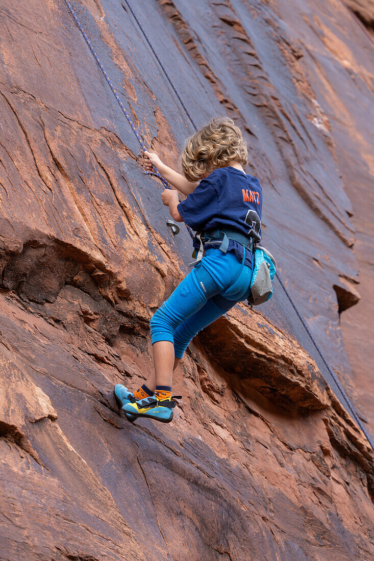 Ein 6-jähriger Junge seilt sich ab, während er im Hunter Canyon bei Moab, Utah, das Klettern lernt.