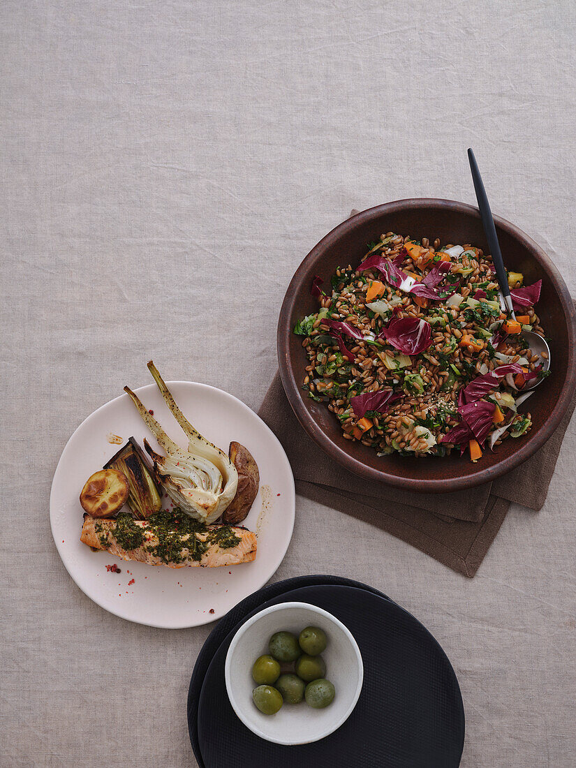 Still life tabletop view healthy Mediterranean meal of spelt salad, grilled salmon with pesto, leeks