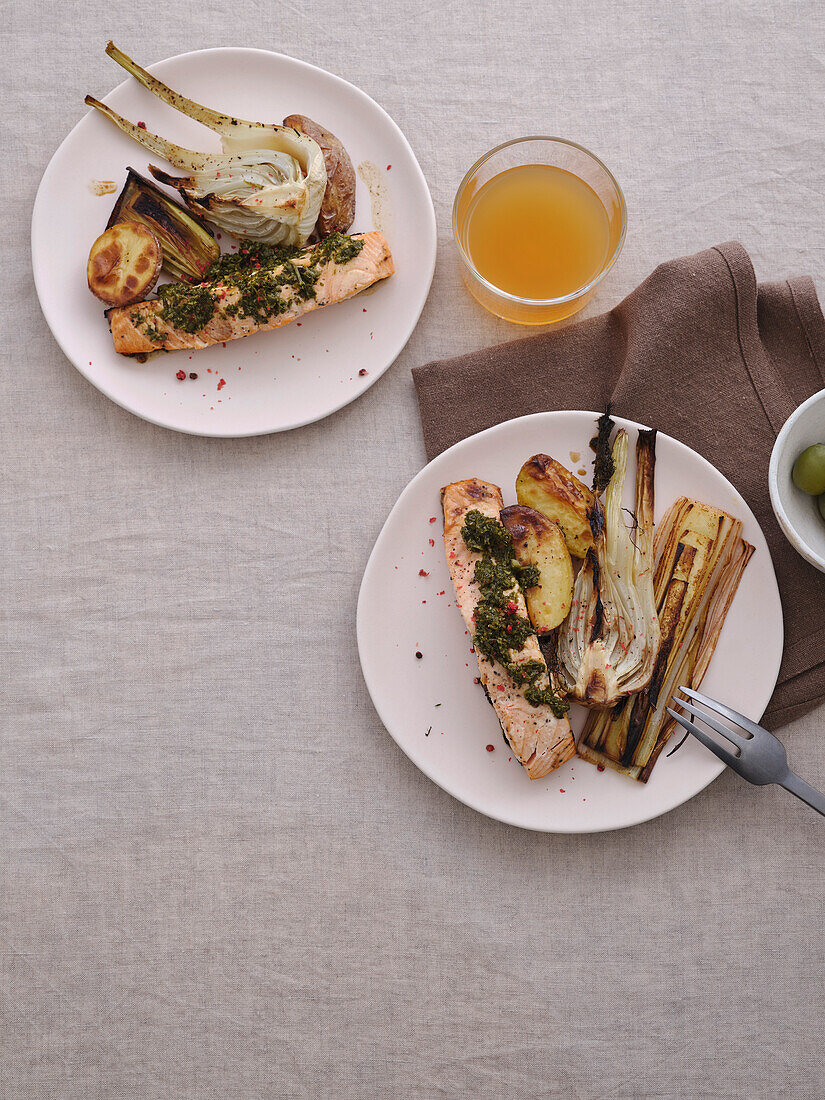 Still life tabletop view gourmet grilled salmon with pesto, baked potatoes, fennel, leek, kombucha