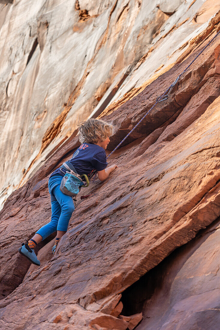 Ein 6-jähriger Junge lernt im Hunter Canyon in der Nähe von Moab, Utah, das Klettern.