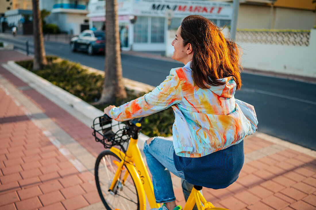 Frau fährt mit dem Fahrrad an der Promenade entlang, Peñiscola, Spanien