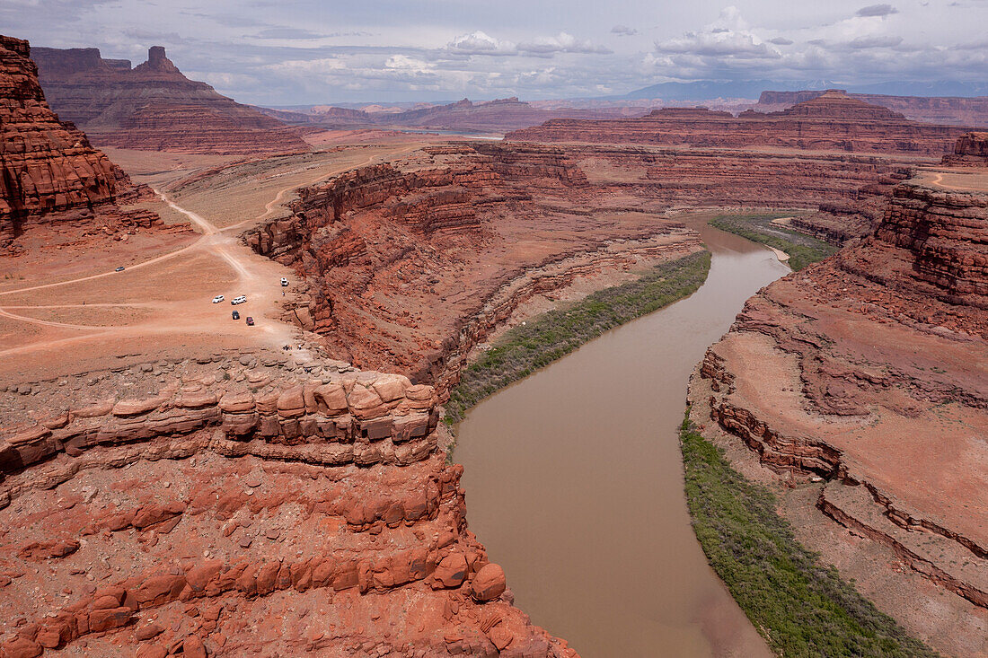 Tourists parked at Thelma and Louise Point on the Shafer Trail by the Colorado River near Moab, Utah. The official name is Fossil Point, but it is the site of the famous scene at the end of the movie, "Thelma and Louise". The Bears Ears National Monument is at right, across the river. Note: The drone was flown legally outside the boundaries of the monument.