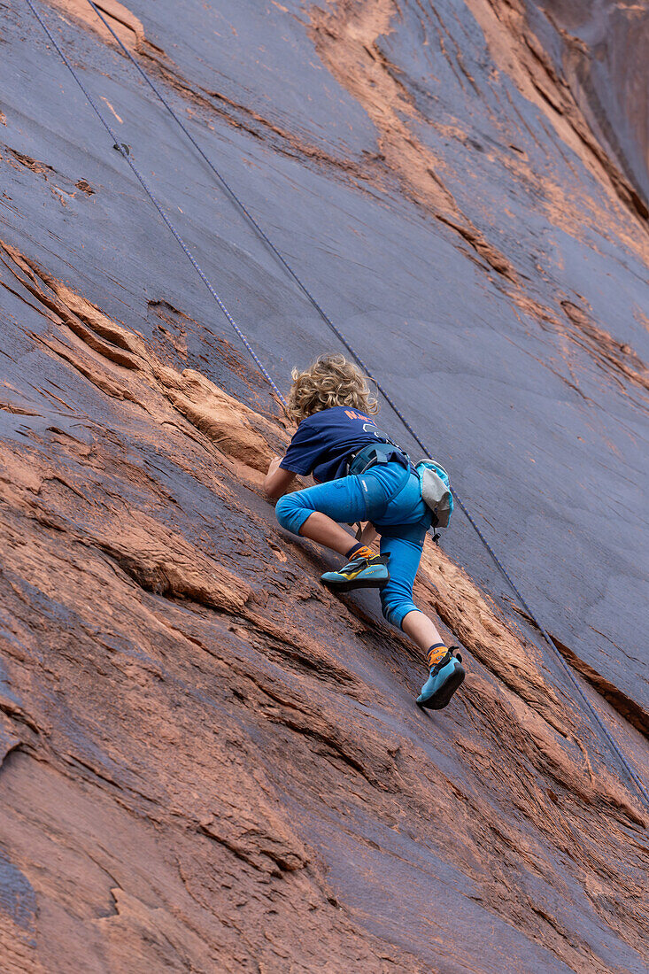 Ein 6-jähriger Junge lernt im Hunter Canyon in der Nähe von Moab, Utah, das Klettern.