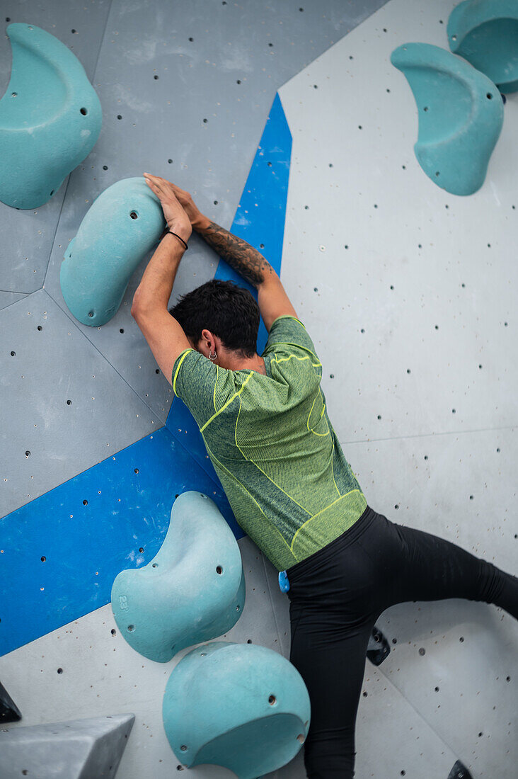 Young man in his twenties climbing on a climbing wall indoors