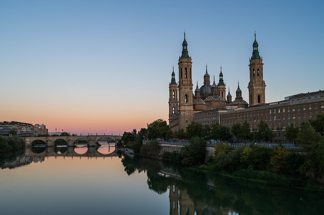 Cathedral-Basilica of Our Lady of the Pillar reflected on the Ebro River at sunset, Zaragoza, Spain