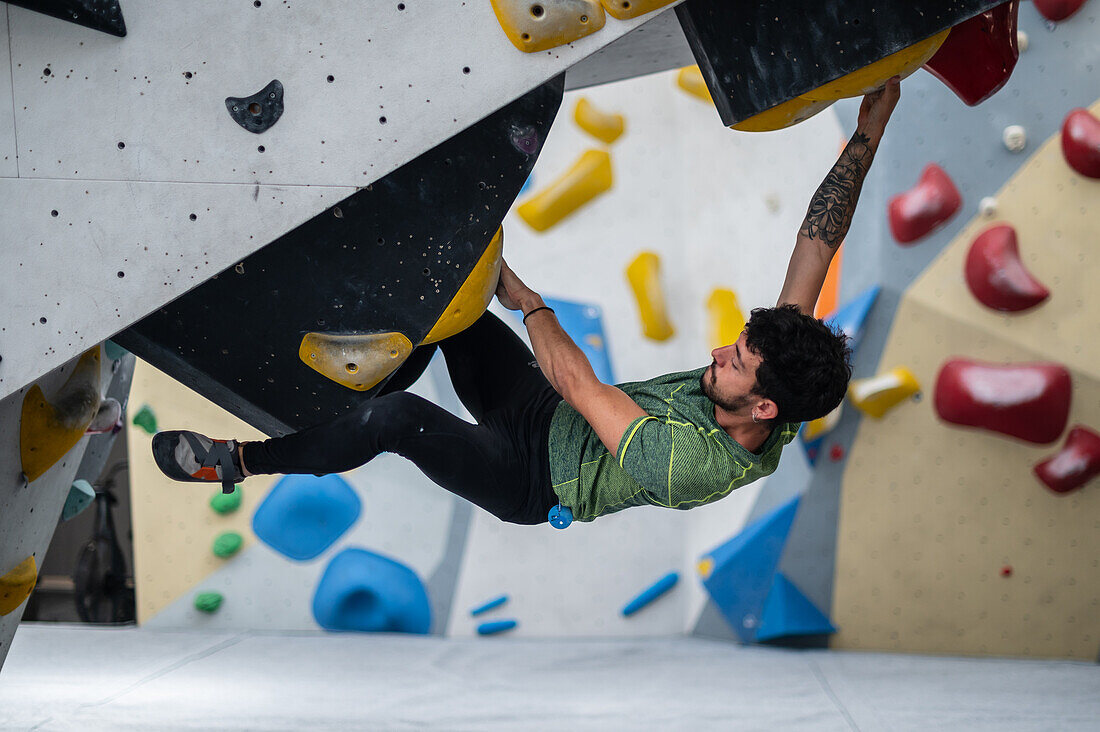 Young man in his twenties climbing on a climbing wall indoors