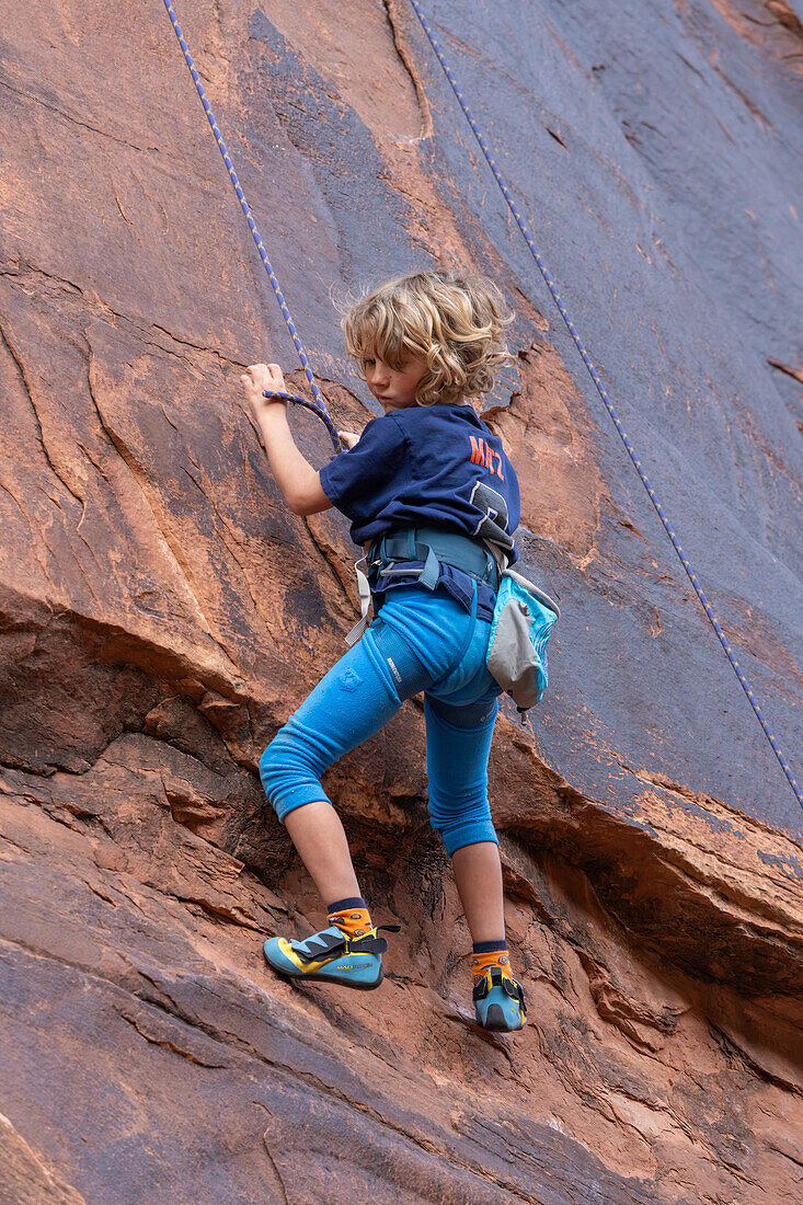 Ein 6-jähriger Junge lernt im Hunter Canyon in der Nähe von Moab, Utah, das Klettern.