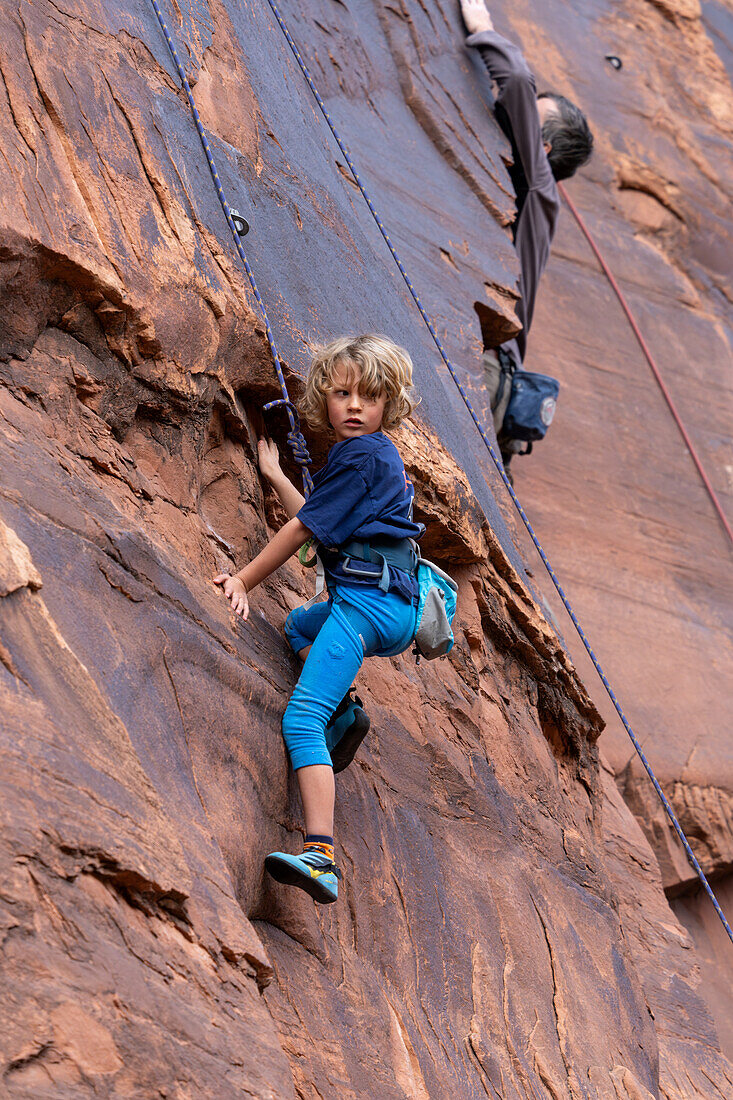 Ein 6-jähriger Junge lernt im Hunter Canyon in der Nähe von Moab, Utah, das Klettern.