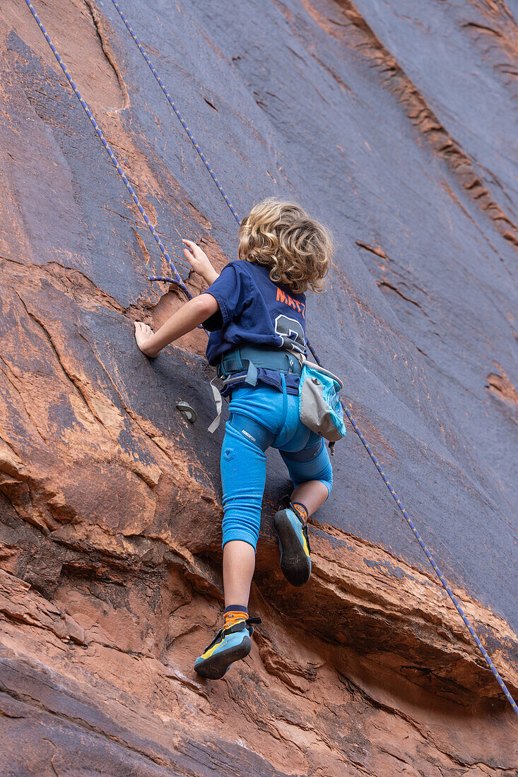 Ein 6-jähriger Junge lernt im Hunter Canyon in der Nähe von Moab, Utah, das Klettern.