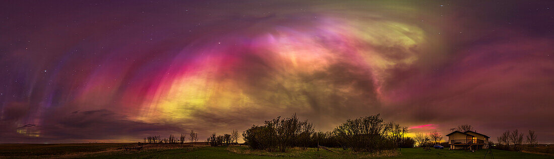 This is a 270º panorama of the May 10/11, 2024 great aurora display, when the Kp Index reached 8 this night bringing aurora to as far south as the southern U.S. Here, from my home in rural southern Alberta, Canada (latitude 51° N) we saw curtains strongly colored green and red from oxygen, but also pink and blue from nitrogen, with the latter colors unusually strong with pinks visible to the naked eye and purples and blues to the camera. Here the pinks stand out despite the extensive amount of cloud about.