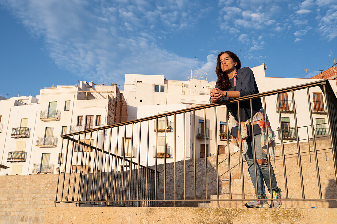 Junge Frau genießt den Sonnenuntergang von der Stadtmauer der Burg Papa Luna in Peñiscola, Castellon, Valencianische Gemeinschaft, Spanien