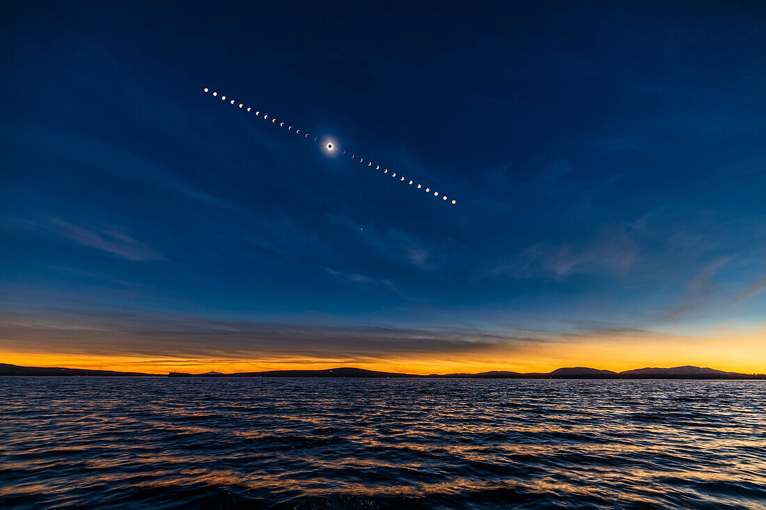 Dies ist die Sequenz der totalen Sonnenfinsternis über den Gewässern des Lac Brome in den Eastern Townships von Quebec, Kanada, am 8. April 2024. Auf die Einzelaufnahme der total verfinsterten Sonne am verdunkelten Finsternishimmel habe ich Bilder der partiellen Phasen vor und nach der Totalität gelegt, die alle 5 Minuten vom Beginn bis zum Ende der Finsternis aufgenommen wurden. Während sich die Sonne von links nach rechts über den Himmel bewegte, bewegte sich der Mond von rechts nach links über die Sonnenscheibe.