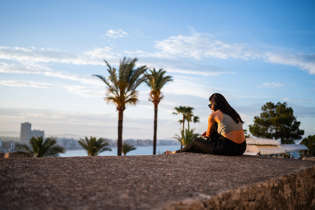 Young woman enjoying the sunset from the city walls of Papa Luna castle in Peñiscola, Castellon, Valencian Community, Spain