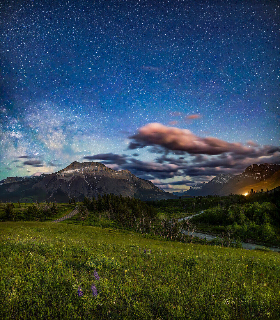 Eine nächtliche Szene unter mondbeschienenem Himmel, auf der Red Rock Canyon Road im Waterton Lakes National Park, Alberta, mit Blick zurück entlang des Pass Creek in Richtung Süden, mit der Milchstraße auf der linken Seite. Waterton ist ein UNESCO-Welterbe.