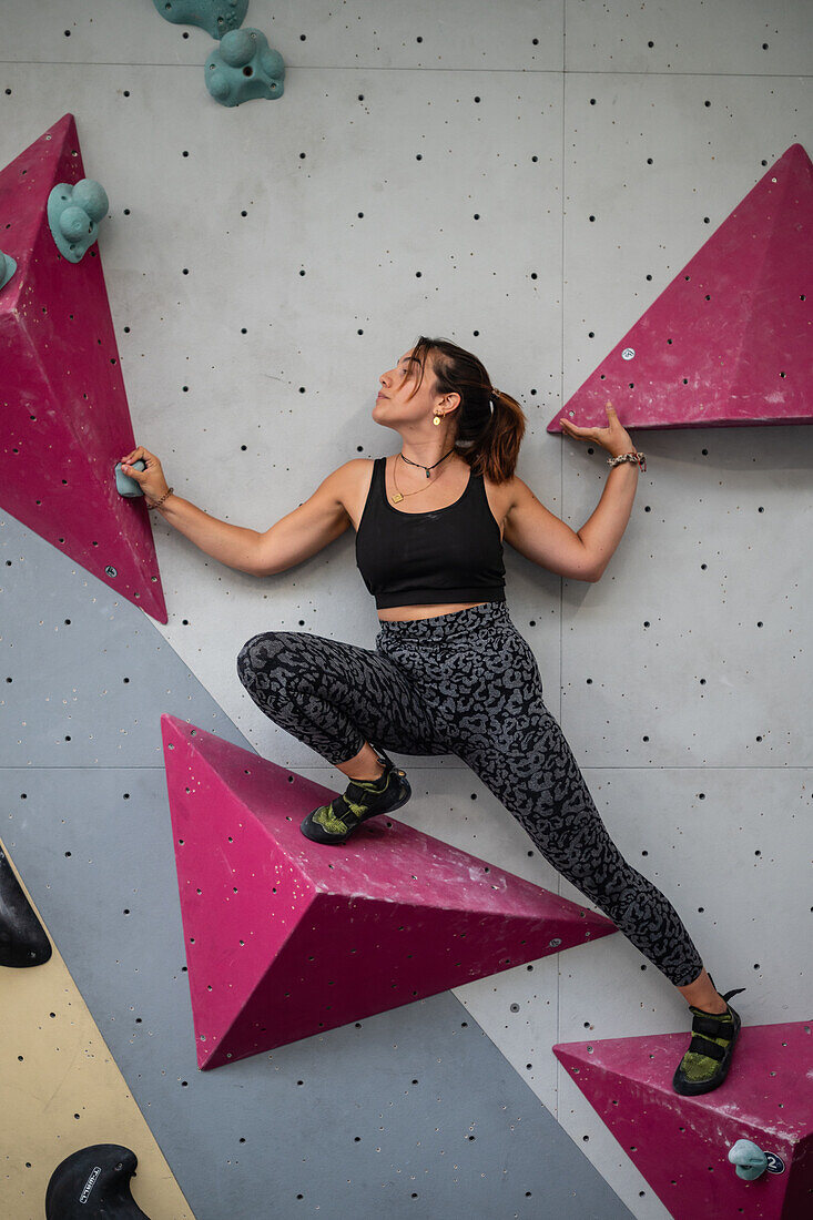 Young man in her twenties climbing on a climbing wall indoors