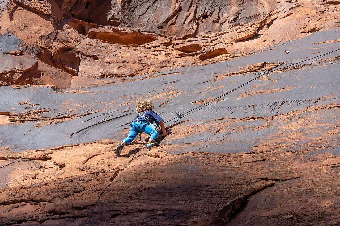 Ein 6-jähriger Junge lernt im Hunter Canyon in der Nähe von Moab, Utah, das Klettern.