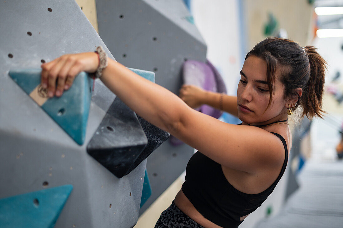 Junger Mann in den Zwanzigern beim Klettern an einer Kletterwand in einer Halle