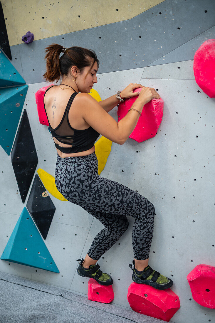 Young man in her twenties climbing on a climbing wall indoors