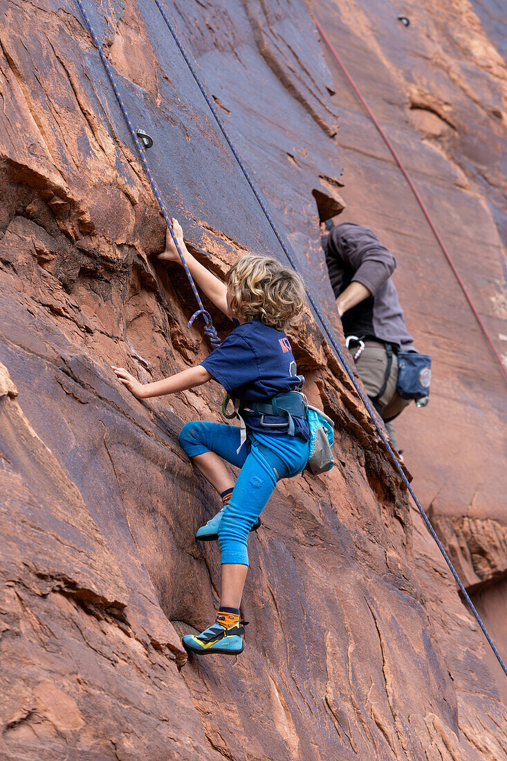 Ein 6-jähriger Junge lernt im Hunter Canyon in der Nähe von Moab, Utah, das Klettern.