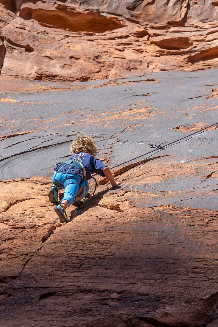 Ein 6-jähriger Junge lernt im Hunter Canyon in der Nähe von Moab, Utah, das Klettern.