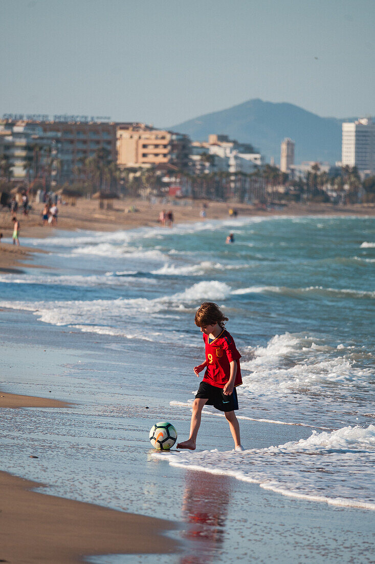 Kleiner Junge spielt mit einem Ball am Strand von Peñiscola, Castellon, Valencianische Gemeinschaft, Spanien