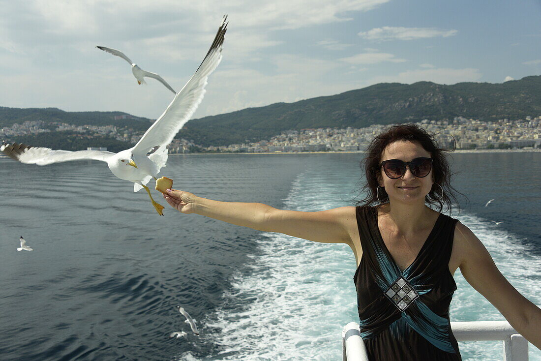 Woman feeding seagulls on a ferry from Kavala to Thassos, North Aegean Sea, Greek Islands, Greece, Europe