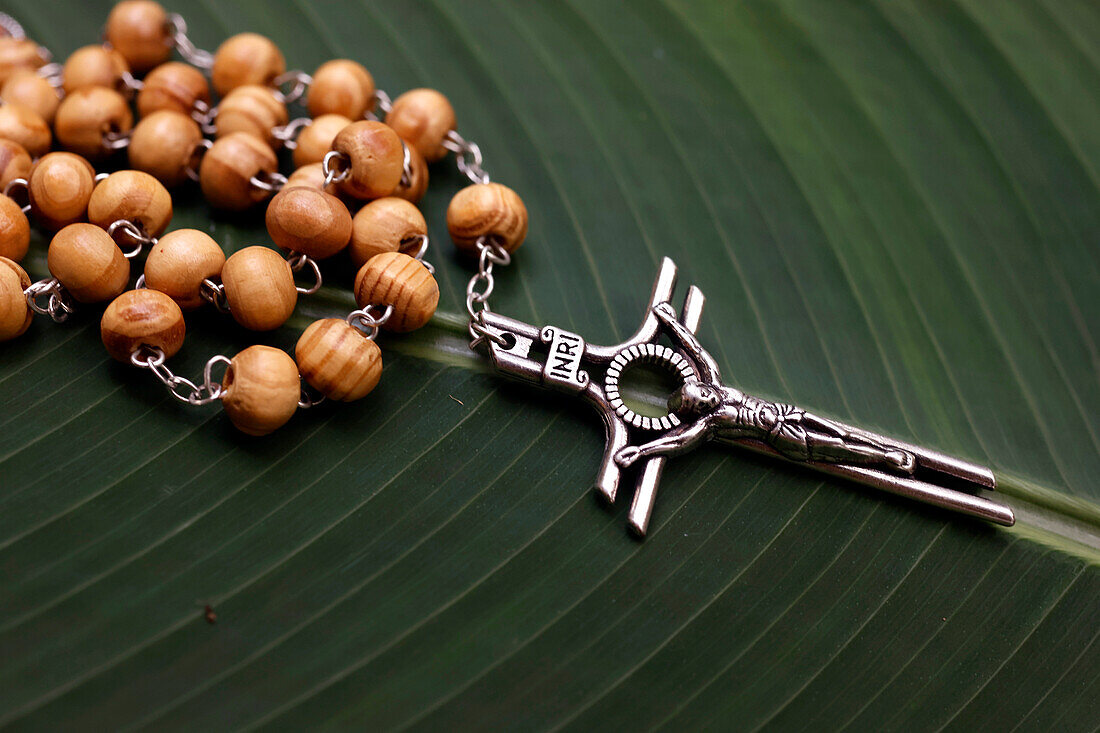 Rosary (prayer beads) on a green leaf, and Jesus on the Cross (Crucifix), Cambodia, Indochina, Southeast Asia, Asia