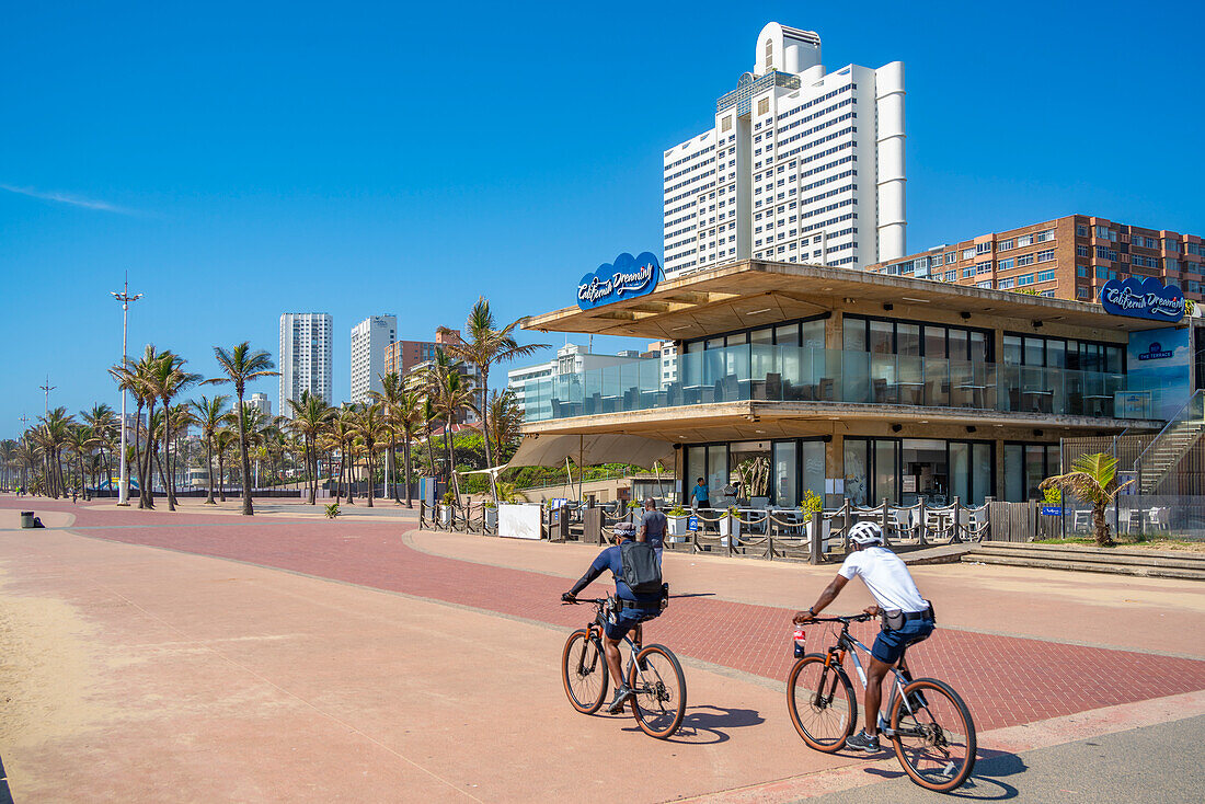 Blick auf Radfahrer, Café und Hotels an der Promenade, Durban, Provinz KwaZulu-Natal, Südafrika, Afrika